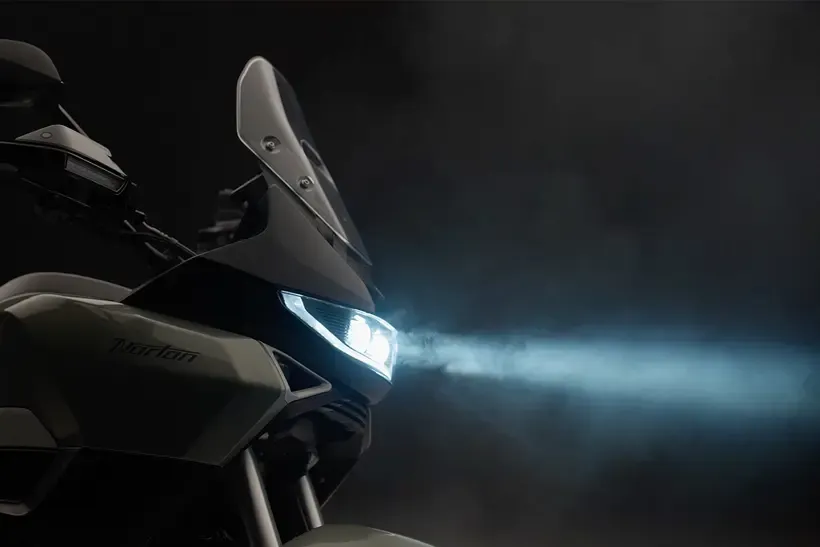 The blue led front lights of the new Norton beaming through smoke on an dark background